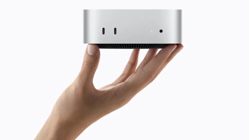 Novo Mac mini prateado sendo segurado por uma mão, com as portas frontais visíveis